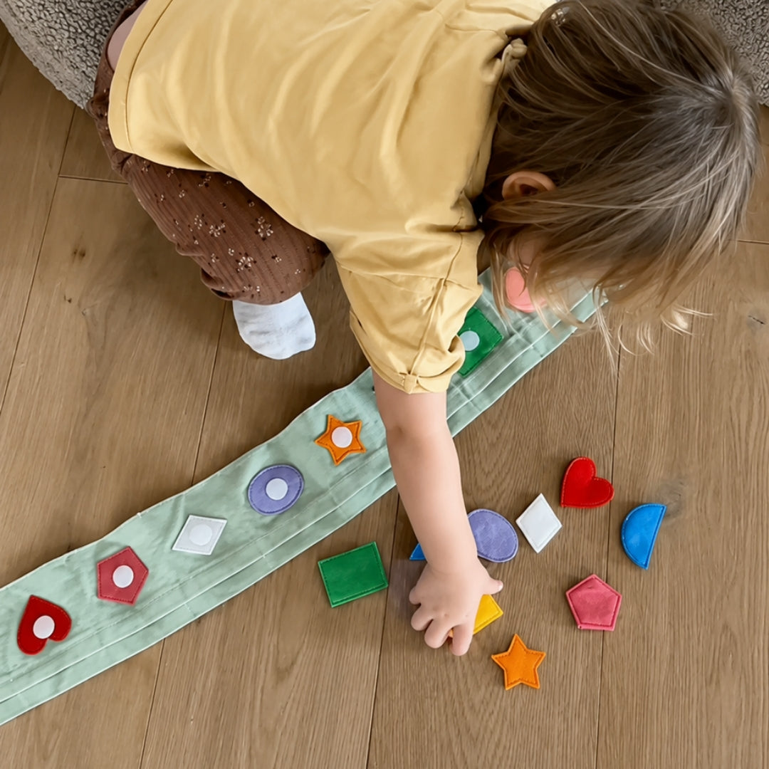 Kind spielt mit Jolly Pockets Bunte Formenwelt auf dem Boden